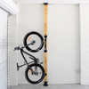 Bicycle mounted against a wooden post with white brick walls.