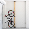 Bicycle mounted against a wooden post with white brick walls.