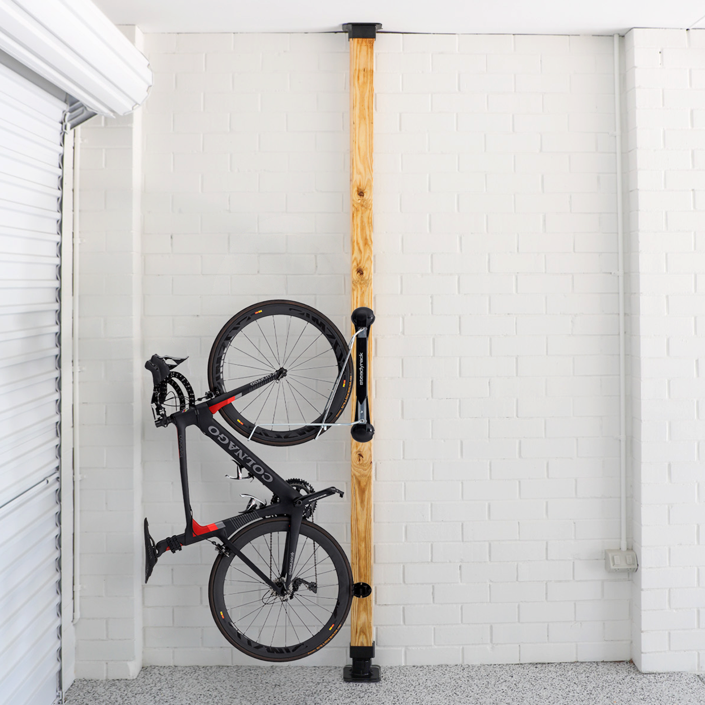 Bicycle installed on a wooden post against a white brick wall.