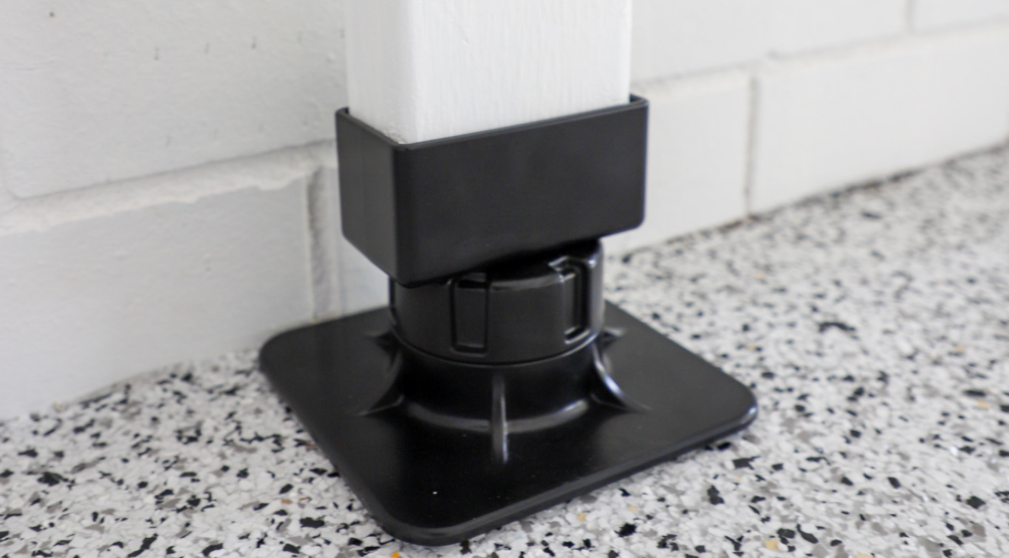 Black plastic base on speckled flooring with white brick wall background