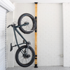 Bicycle mounted against a wooden post with white brick walls.