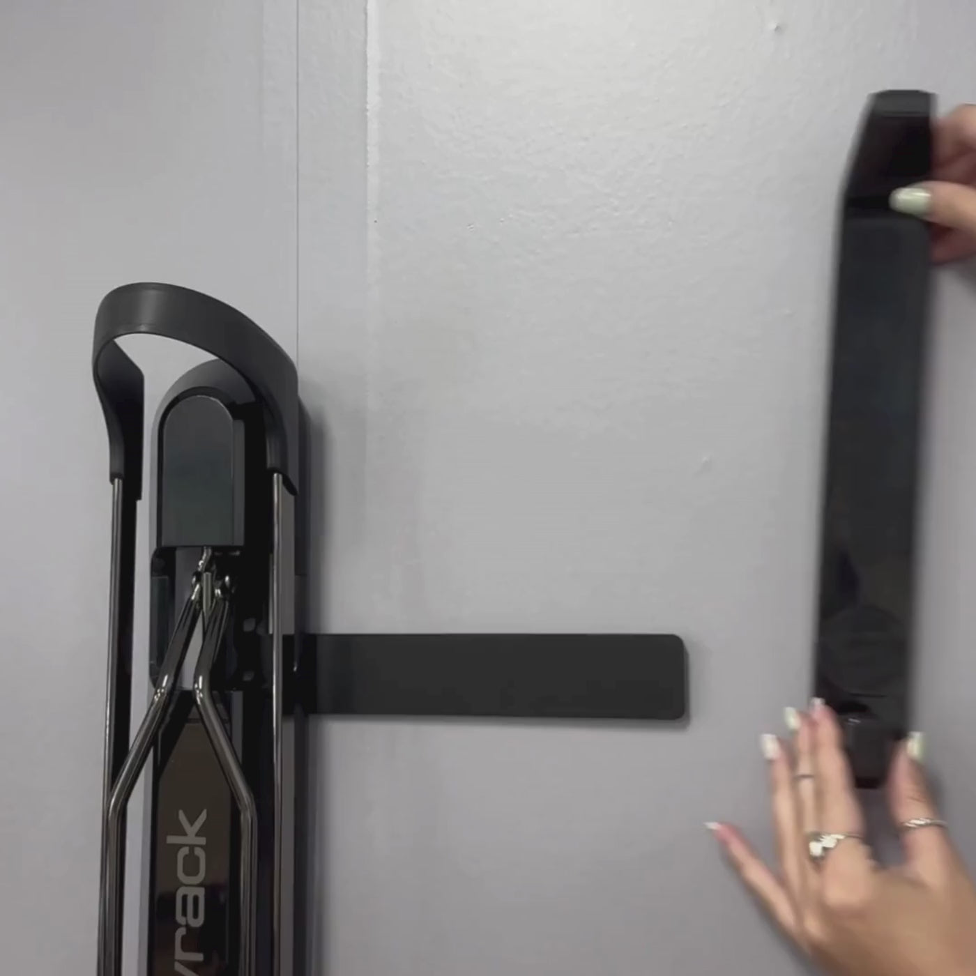 A person sliding a helmet hook onto a GearMate bracket.